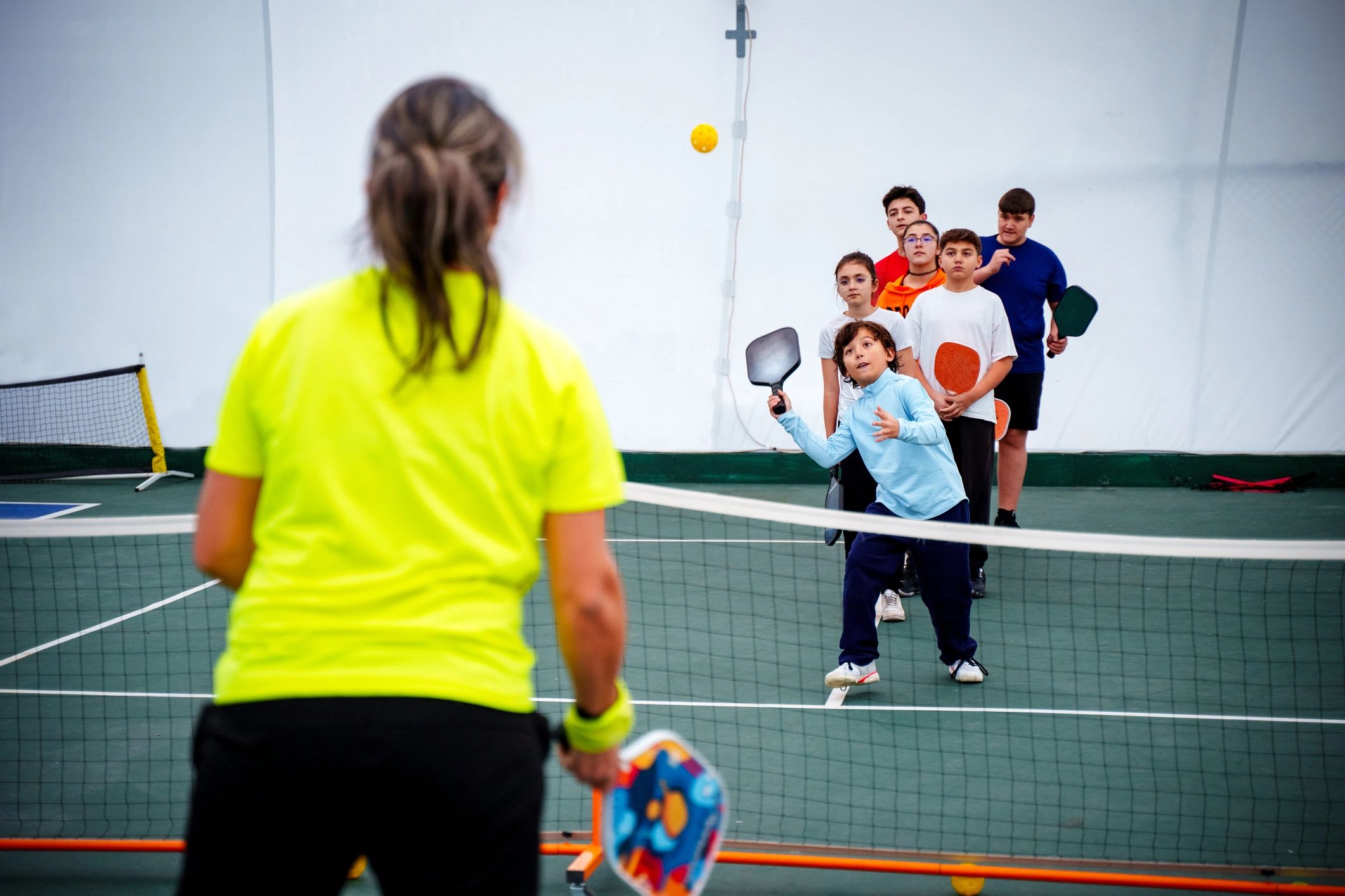 Coach leading a pickleball training session indoors